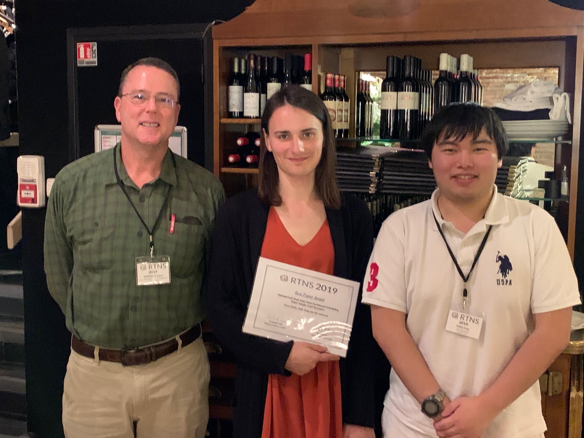 Peter Tong, Clara Hobbs, and James Anderson in Paris, France holding the RTNS best paper award
