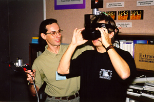At the Visualization '98 Open House, Rui Bastos helps Jarek 
Rossignac with the Walking Experience (Photo by Todd Gaul)